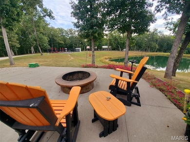 View of patio featuring a water view, a fire pit, and view of scattered trees