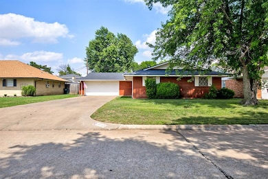Ranch-style home featuring concrete driveway, a front yard, brick siding, and a garage