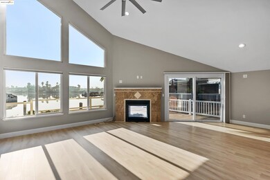 Unfurnished living room featuring a tile fireplace, ceiling fan, a water view, wood finished floors, and recessed lighting