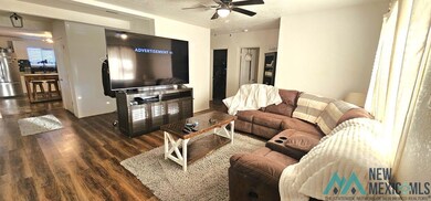 Living room with dark wood-style floors, a textured ceiling, and a ceiling fan