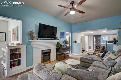 Living room featuring ceiling fan, carpet, and a f