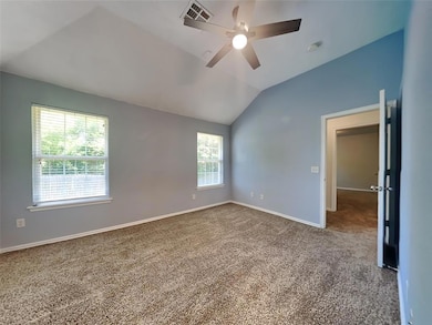 Carpeted spare room featuring vaulted ceiling, ceiling fan, baseboards, and a smoke detector