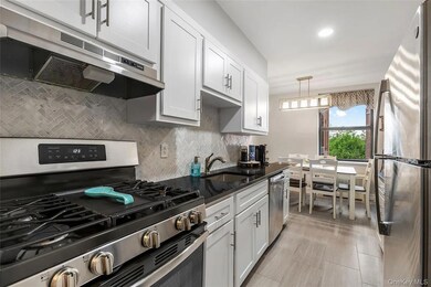 Kitchen with appliances with stainless steel finishes, decorative backsplash, under cabinet range hood, recessed lighting, and white cabinets