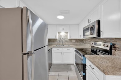 Kitchen with a sink, light tile patterned floors, tasteful backsplash, and stainless steel appliances