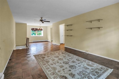 Empty room featuring a chandelier, ceiling fan, and baseboard heating