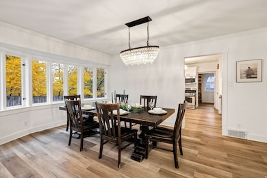 Dining area with light wood-style flooring, crown molding, and a chandelier