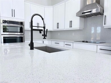 Kitchen with black electric stovetop, wall chimney