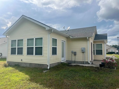 Rear view of property featuring a lawn, a shingled roof, and a patio