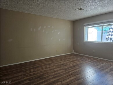 Empty room with dark wood-style floors, a textured
