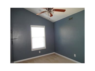 Empty room featuring ceiling fan, vaulted ceiling, baseboards, and light carpet