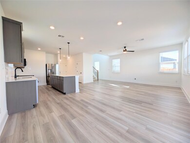 Unfurnished living room featuring plenty of natural light, light wood-type flooring, recessed lighting, a ceiling fan, and stairs