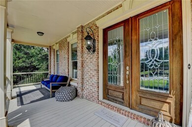 Entrance to property with covered porch, brick siding, and french doors