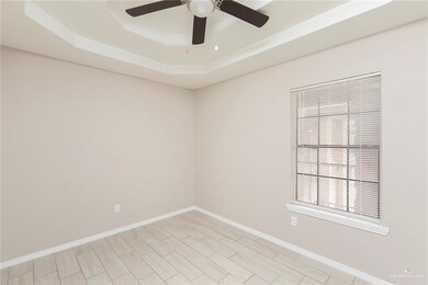Empty room featuring a ceiling fan, a raised ceiling, and baseboards