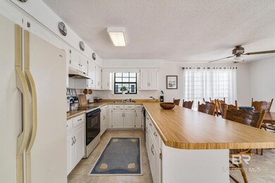 Kitchen with white fridge, a peninsula, electric range oven, a kitchen breakfast bar, and white cabinets