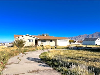 Ranch-style home featuring a mountain view, a chimney, a garage, stucco siding, and driveway
