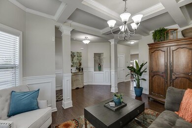 Living room featuring ornate columns, coffered cei