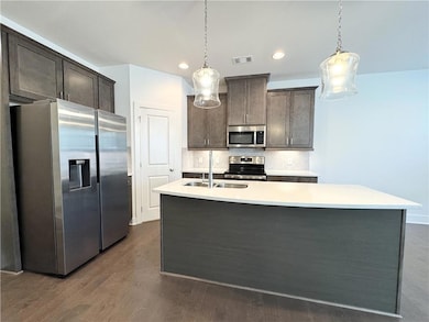 Kitchen featuring appliances with stainless steel finishes, tasteful backsplash, dark brown cabinets, hanging light fixtures, and recessed lighting