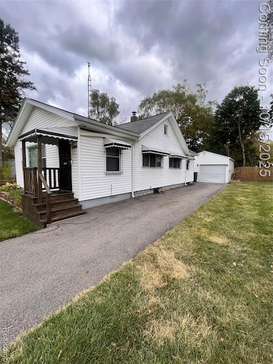 View of front of house featuring a chimney, an outdoor structure, and a detached garage