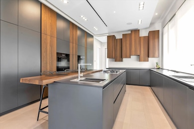 Kitchen featuring modern cabinets, a breakfast bar area, a center island, gray cabinetry, and stainless steel gas cooktop