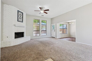 Unfurnished living room featuring ceiling fan with notable chandelier, a textured ceiling, a brick fireplace, and carpet