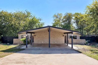 View of front of home featuring driveway, brick siding, and an attached carport