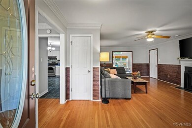 Living room with ceiling fan with notable chandelier, ornamental molding, and hardwood / wood-style floors