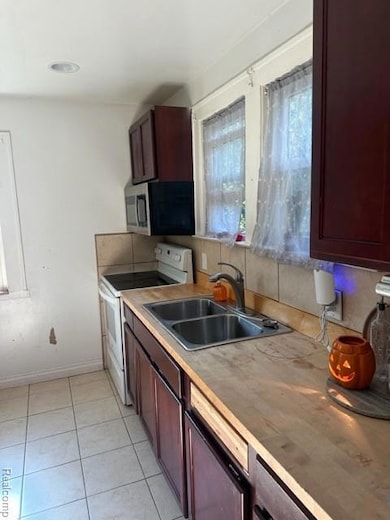 Kitchen with stainless steel range oven, light tile patterned floors, light countertops, and dark brown cabinetry