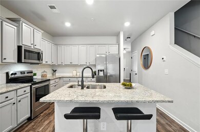 Kitchen featuring stainless steel appliances, dark wood-style floors, an island with sink, backsplash, and recessed lighting