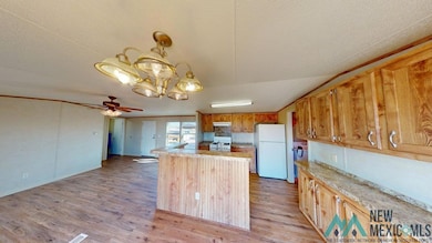 Kitchen featuring a chandelier, white appliances, light wood-type flooring, a center island, and pendant lighting