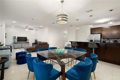 Dining space with ceiling fan with notable chandelier and light tile patterned flooring