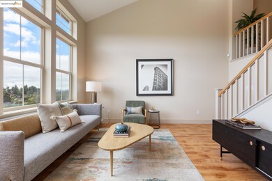 Living area with high vaulted ceiling, light wood finished floors, and stairway