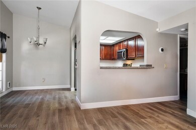 Kitchen with stainless steel microwave, a chandelier, lofted ceiling, dark wood-type flooring, and arched walkways