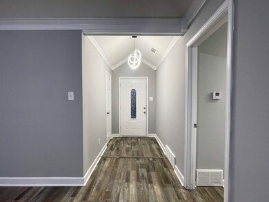 Doorway to outside featuring crown molding, dark h