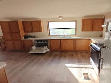 Kitchen with light countertops, white appliances, light wood-type flooring, and brown cabinetry