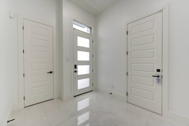 A bright and modern foyer with polished tile flooring, clean white walls, and a frosted glass front door.