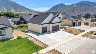 View of front of home with a residential view, a garage, driveway, a mountain view, and a front yard