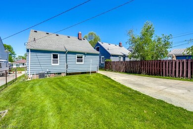 Rear view of house with central air condition unit and a lawn