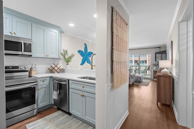 Kitchen featuring stainless steel appliances, ornamental molding, gray cabinetry, tasteful backsplash, and light countertops