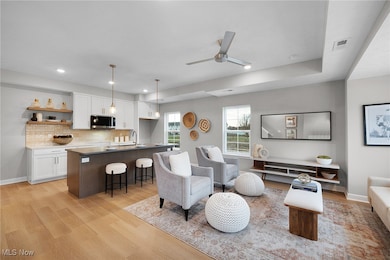 Living room featuring light wood finished floors, a ceiling fan, and recessed lighting