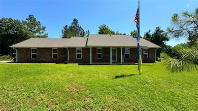 Ranch-style house with a front yard, brick siding, and a patio