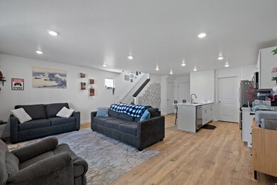 Living room with light wood finished floors, stairway, and recessed lighting