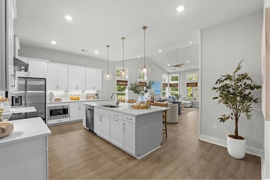 Kitchen featuring open floor plan, decorative light fixtures, white cabinetry, recessed lighting, and light wood-style flooring