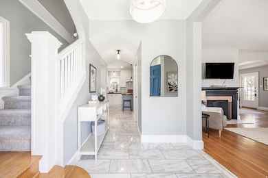 Entryway featuring stairs, arched walkways, light marble finish floors, and plenty of natural light