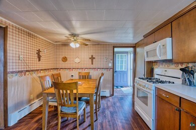 Dining area featuring wallpapered walls, a baseboard heating unit, dark wood-type flooring, and a ceiling fan