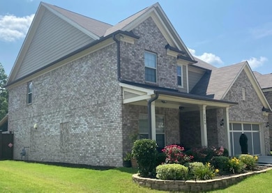 View of home's exterior with brick siding, a garage, a lawn, and covered porch
