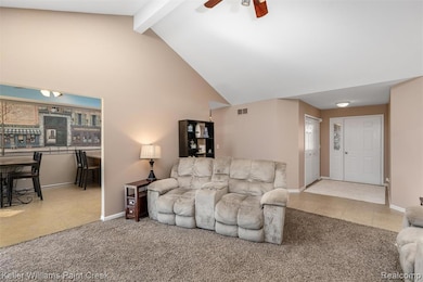 Living room with light tile patterned floors, beamed ceiling, light colored carpet, high vaulted ceiling, and ceiling fan