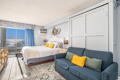 Bedroom featuring access to outside, a textured ceiling, wood finished floors, and a wall mounted AC