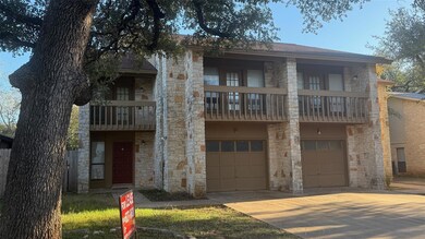 View of front of home featuring stone siding, a garage, a balcony, and driveway