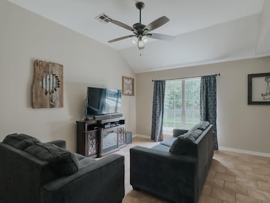 Tiled living room featuring vaulted ceiling and ceiling fan
