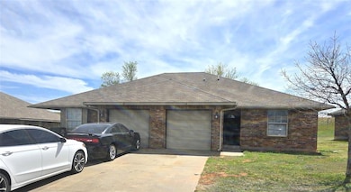 Ranch-style home with driveway, brick siding, a ga